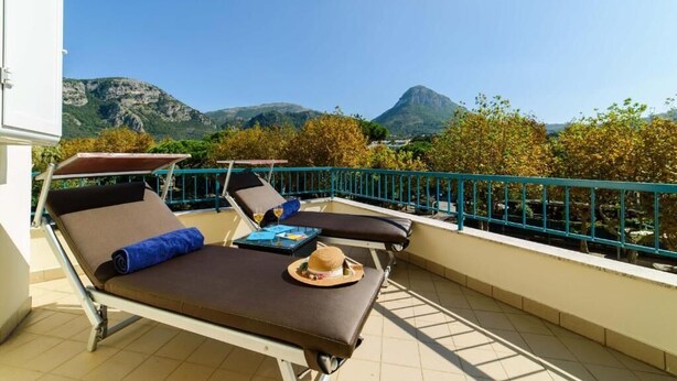 A balcony with two sun loungers, a hat, and a tray table.