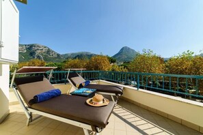 A balcony with two sun loungers, a hat, and a tray table.