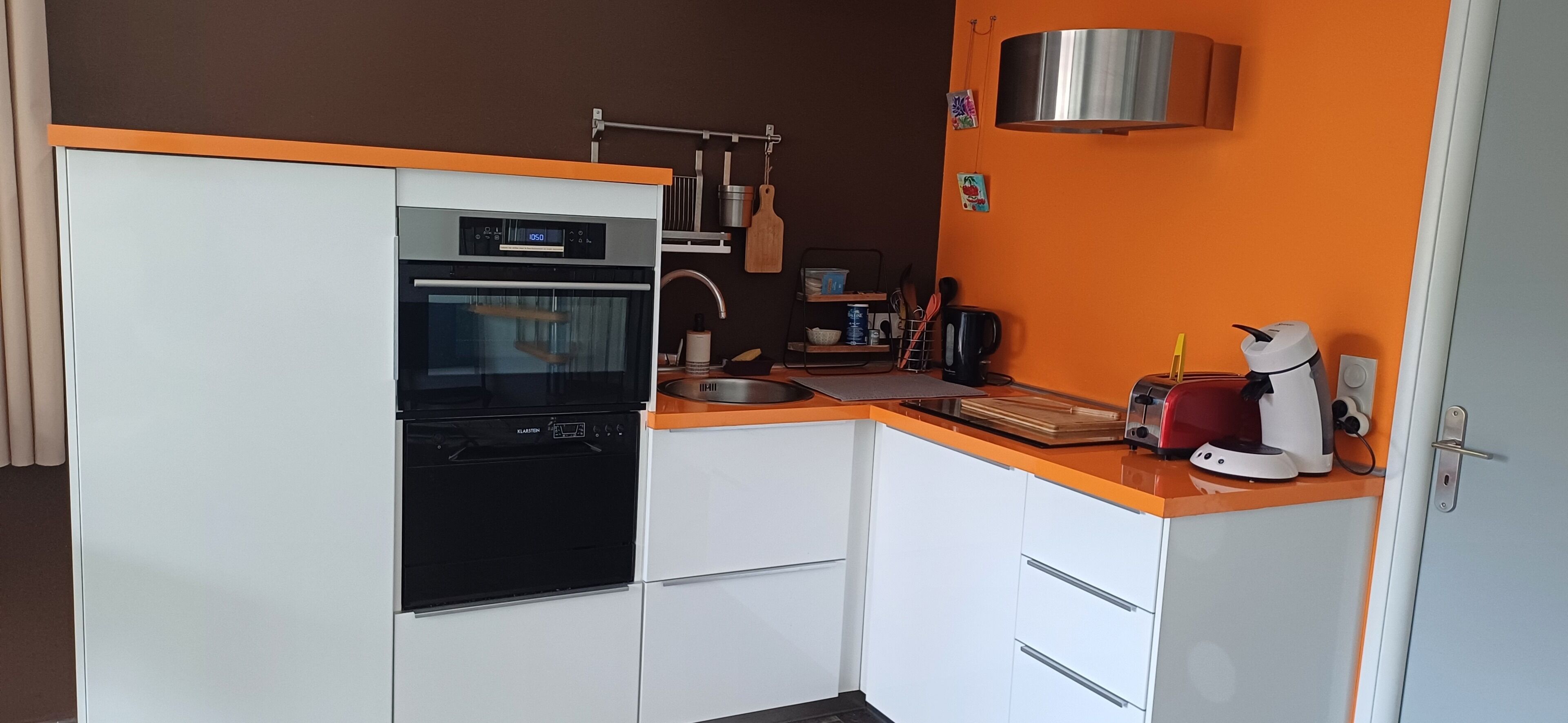 A compact kitchen with a built-in oven, a coffee maker, and a toaster.