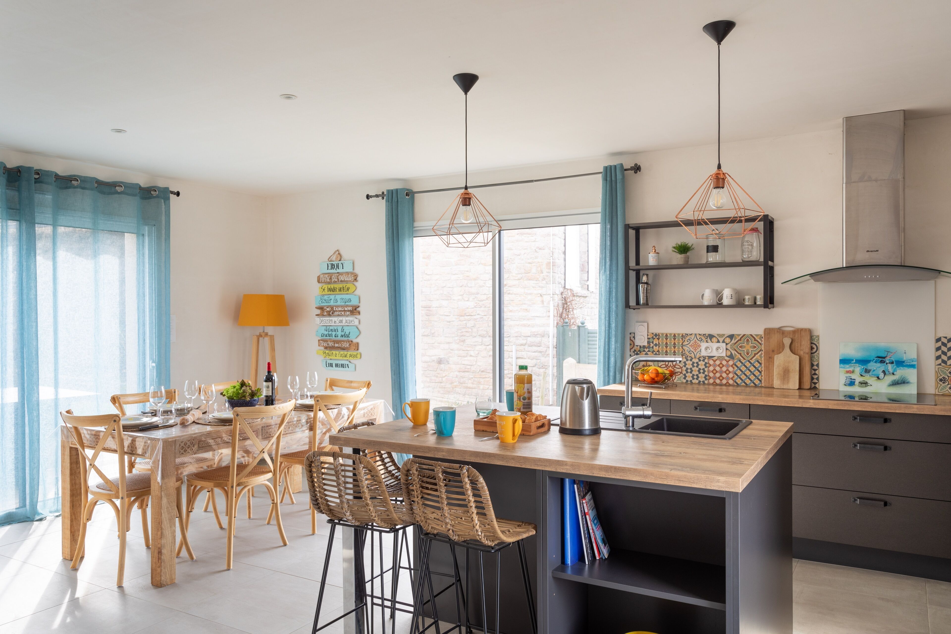 Een moderne keuken met een houten keukeneiland, barstoelen en hanglampen.