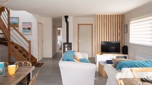 A modern living room with a sofa, TV, and a fireplace. - Côte et mer - Proche plage, parking privé (Erquy)