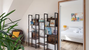 A modern bedroom with a wooden bed, a bookshelf, and a large mirror. - Côte et mer - Proche plage, parking privé (Erquy)