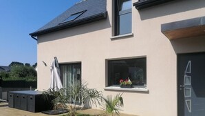 A modern two-story house with a flat roof, large windows, and a small garden area with a palm tree and potted plants. - Côte et mer - Proche plage, parking privé (Erquy)