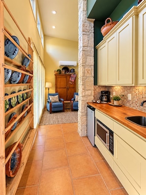 A kitchen with a stone column, a coffee maker, and a dishwasher. - Modern pool side guest suite compliments Historic 1903 Boerne Home walk to town! (Boerne)