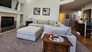 A spacious living room with a fireplace, a sofa, a coffee table, and a staircase leading to an upper level. - Spacious 5BR Retreat by Trails Pet-Friendly (Parker)