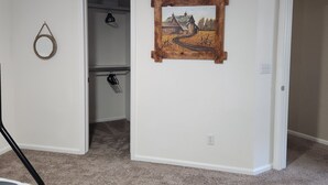 A hallway with a closet, a coat rack, and a painting of a rural scene. - Spacious 5BR Retreat by Trails Pet-Friendly (Parker)