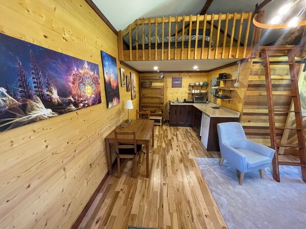Un interior de madera acogedor con comedor, cocina y habitaci ón en entrepiso.