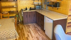 Una cocina pequeña con armarios de madera, un lavamanos, un tostador y un refrigerador.