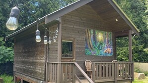 Una cabaña de madera con porche, escaleras y un mural en la pared.