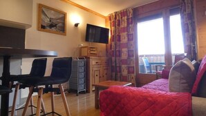 Une pièce confortable avec un lit, un bureau avec des chaises, une télévision et une fenêtre avec des rideaux.
