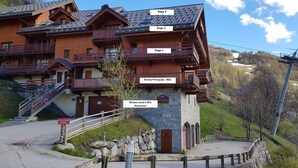 Un immeuble en bois à plusieurs étages, doté de balcons, avec les indications « 1er étage », « 2e étage » et « 3e étage ».
