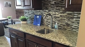 A kitchen with granite countertops, dark wooden cabinets, a stainless steel sink, and a mosaic backsplash. - Lakefront Condo 2br/2ba 208 indoor pool, beach/balcony. Rent 3/4th free-ask (Geneva)