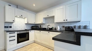 Una cocina moderna con armarios blancos, encimera negra y suelo de madera.