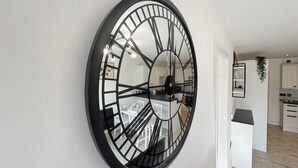 Una cocina moderna con armarios blancos, un reloj negro y suelo de madera.