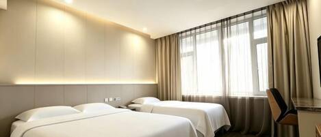 A hotel room with two beds, a desk, and a large window with curtains.