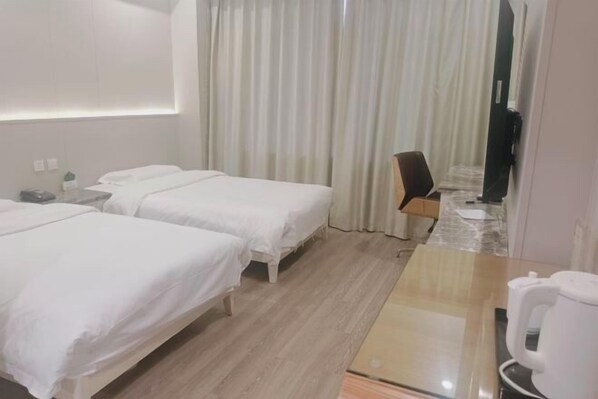 Quarto de hotel com duas camas, uma mesa com cafeteira e uma cadeira.