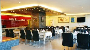 A restaurant with a red counter, black chairs, and white tables. - Duoflai Hotel (Mudanjiang High-speed Railway Station No.4 Middle School) (Mudanjiang)