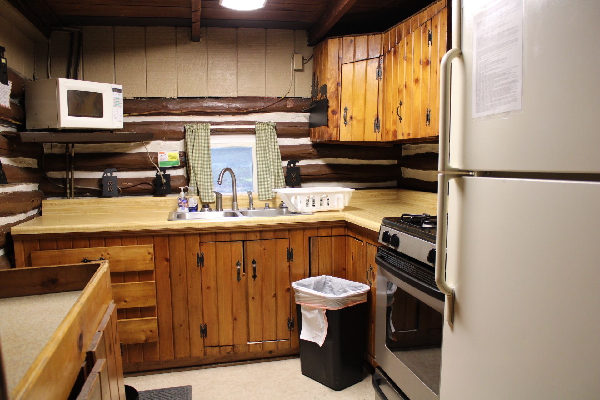 A compact kitchen with wooden cabinets, a white refrigerator, a stove, and a microwave.