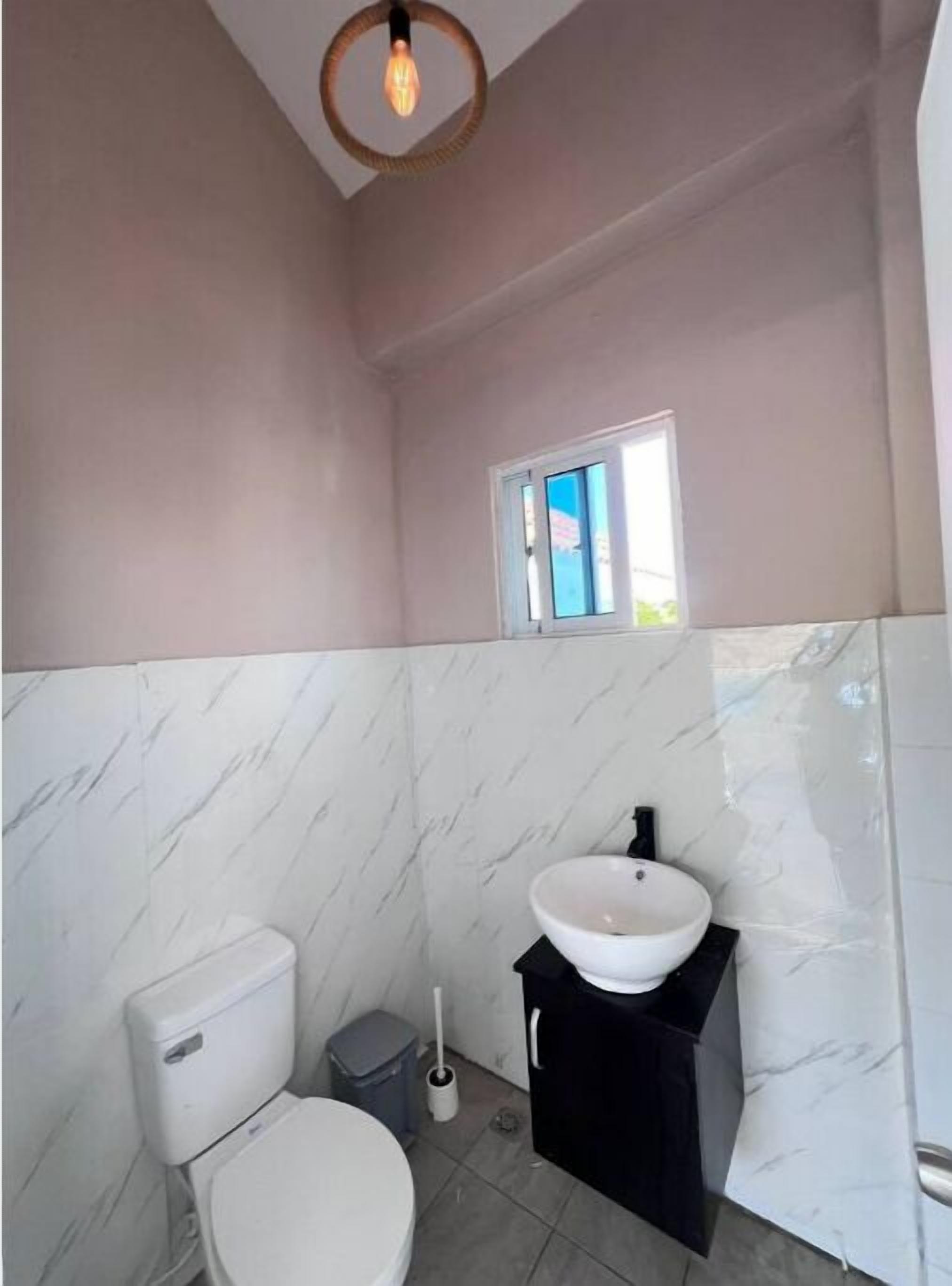 A bathroom with a toilet, sink, and window.