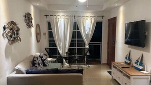 A modern living room with a sofa, TV, and decorative items.