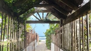 A covered walkway leading to a beach, with metal railings on both sides and a view of the ocean.