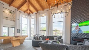 A spacious living area with a foosball table, grey sofas, a large flat-screen TV, and a fireplace. - Remodeled 2-Queen 2BR Suite | Retail & Sun Oasis (Scottsdale)