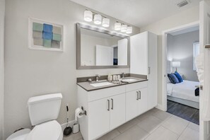 A modern bathroom with a toilet, sink, and mirror. - Trendy One Bedroom Getaway Steps from Biscayne (Miami)