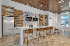 A modern kitchen with a central island, bar area, and wooden flooring. - Trendy One Bedroom Getaway Steps from Biscayne (Miami)