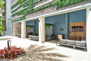 A modern outdoor seating area with tiered planters, a cityscape view, and a lounge chair. - Trendy One Bedroom Getaway Steps from Biscayne (Miami)