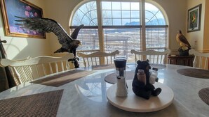 A dining area with a large oval window, a white table with a central sculpture, and a wooden cabinet in the background. - Yellowstone Riverside 3 Bedrooms 2.5 Bathroom Home with Panoramic Park Views (Gardiner)