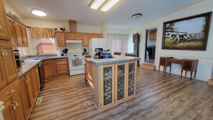 A spacious kitchen with wooden cabinets, a central island, and a painting on the wall. - Yellowstone Riverside 3 Bedrooms 2.5 Bathroom Home with Panoramic Park Views (Gardiner)