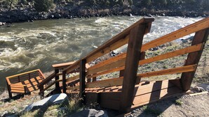 A wooden staircase leading down to a river, surrounded by rocks and greenery. - Yellowstone Riverside 3 Bedrooms 2.5 Bathroom Home with Panoramic Park Views (Gardiner)