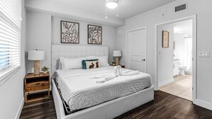 A modern bedroom with a large bed, two bedside tables, a ceiling fan, and artwork on the wall.