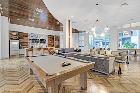 A modern interior with a pool table, bar area, and seating arrangements.