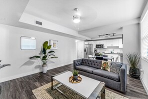 A modern living room with a gray sofa, a white coffee table, and a potted plant.