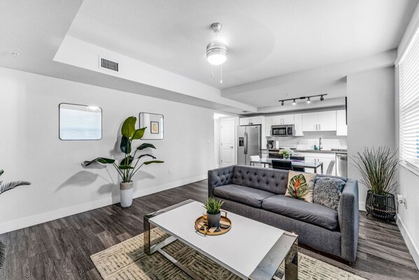 A modern living room with a gray sofa, a white coffee table, and a potted plant.