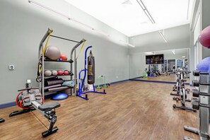 Een sportschool met trainingsapparatuur, een bokszak en een spiegelwand.