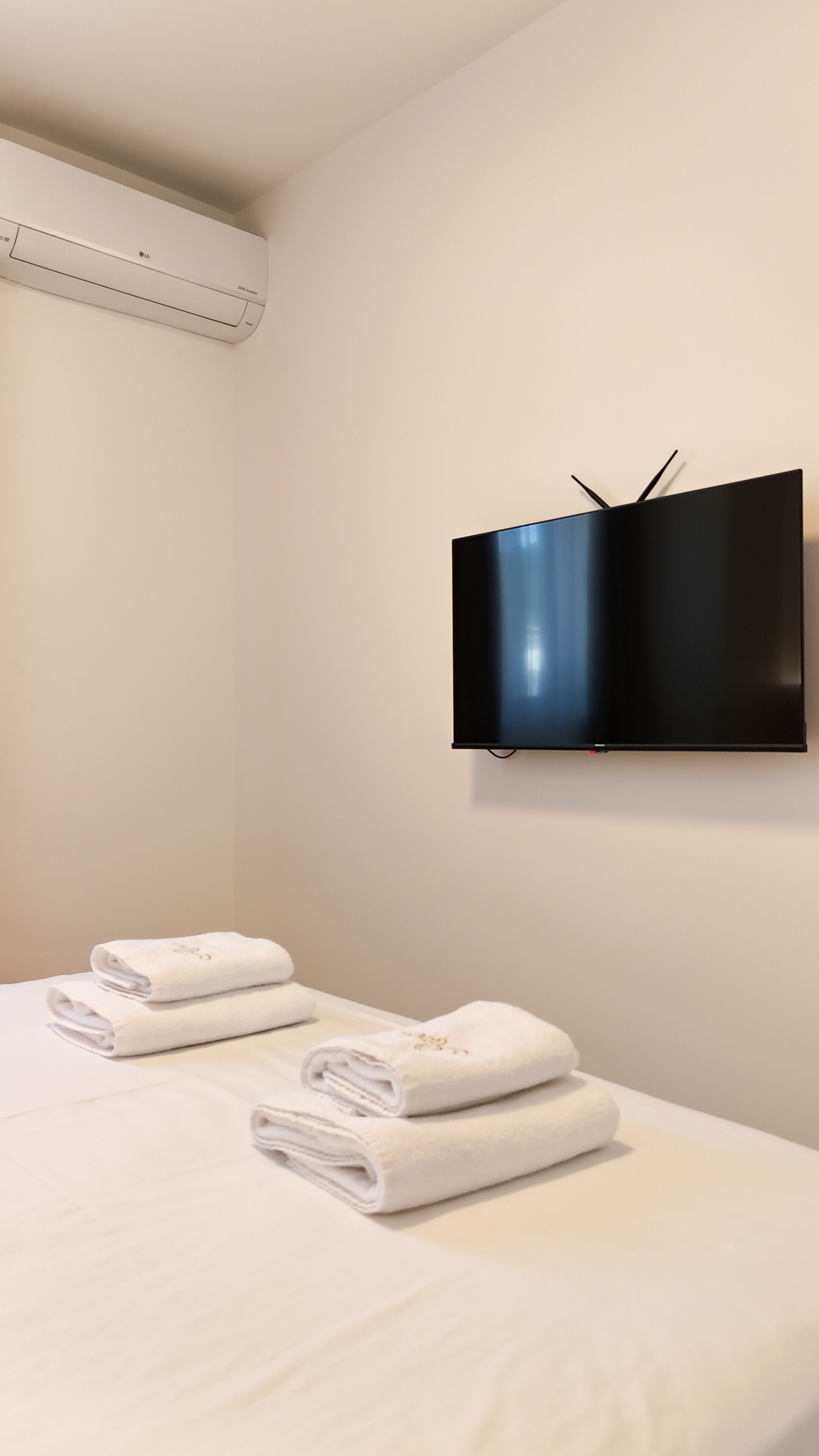 Habitación de hotel con cama, televisor de pantalla plana montado en la pared y aire acondicionado en el techo.