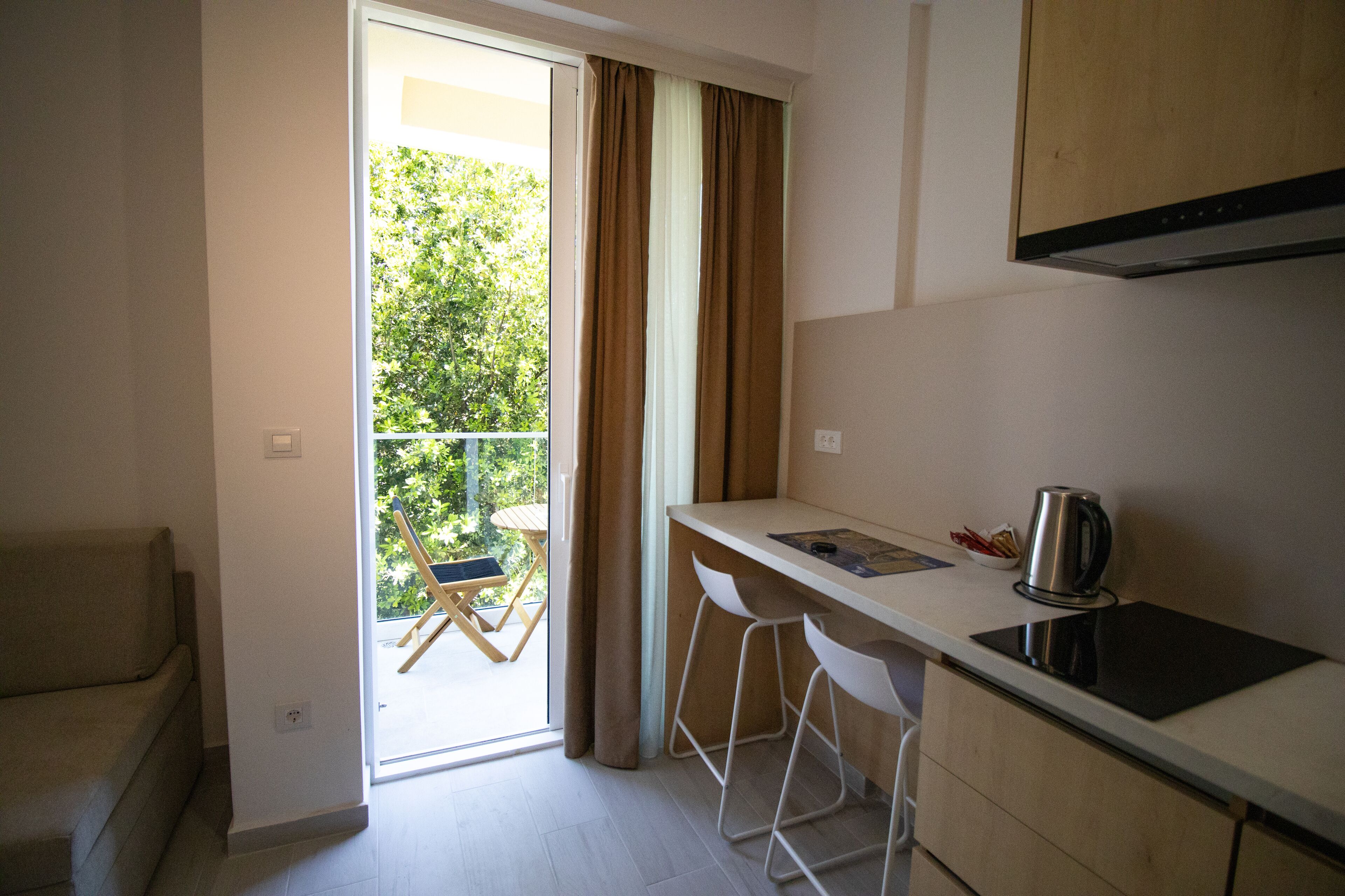A compact kitchen with a sliding glass door leading to a balcony, a sofa, and a small dining area.