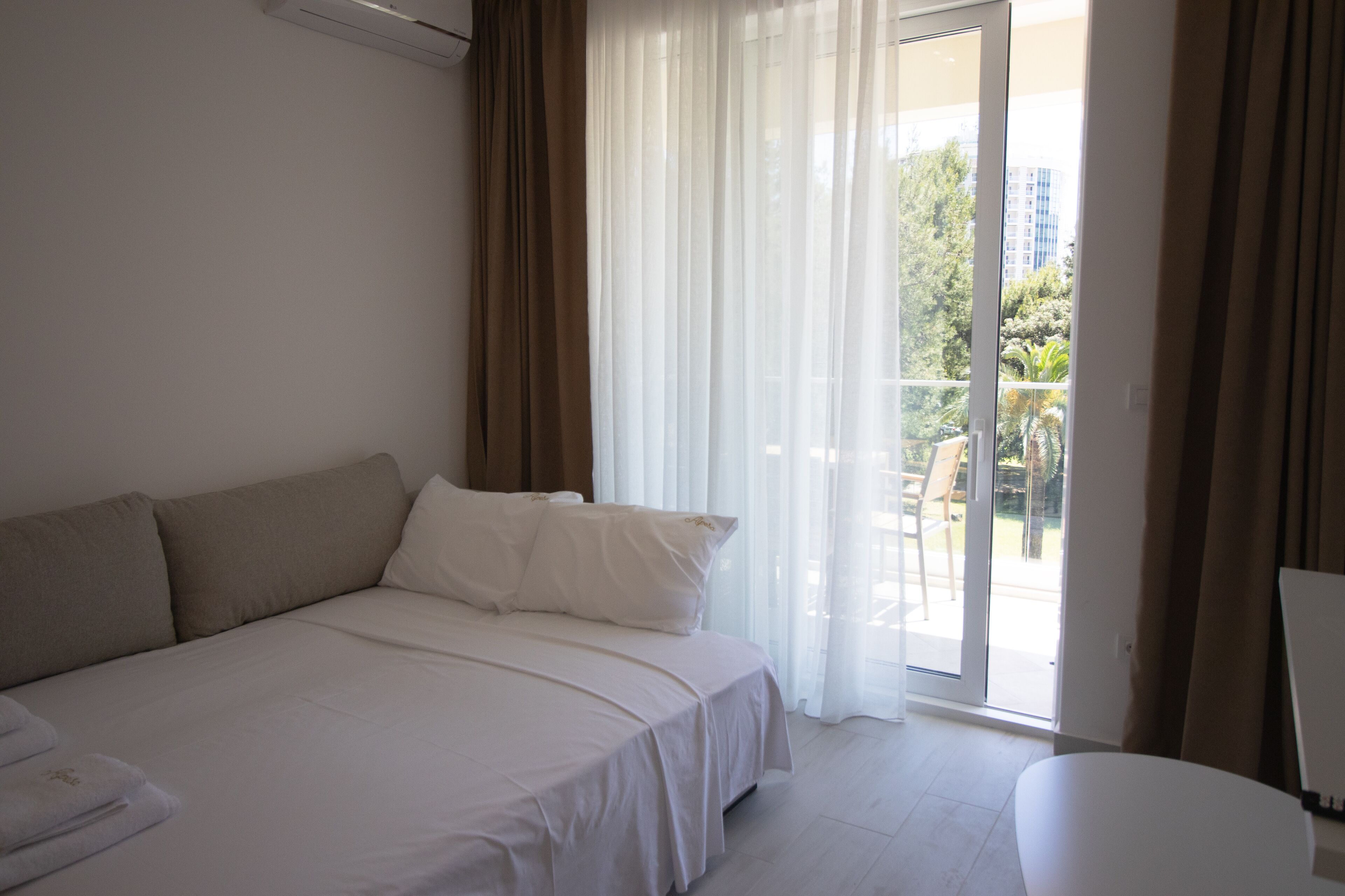 Habitación de hotel con una cama, una mesa y vistas al exterior a través de un ventanal.