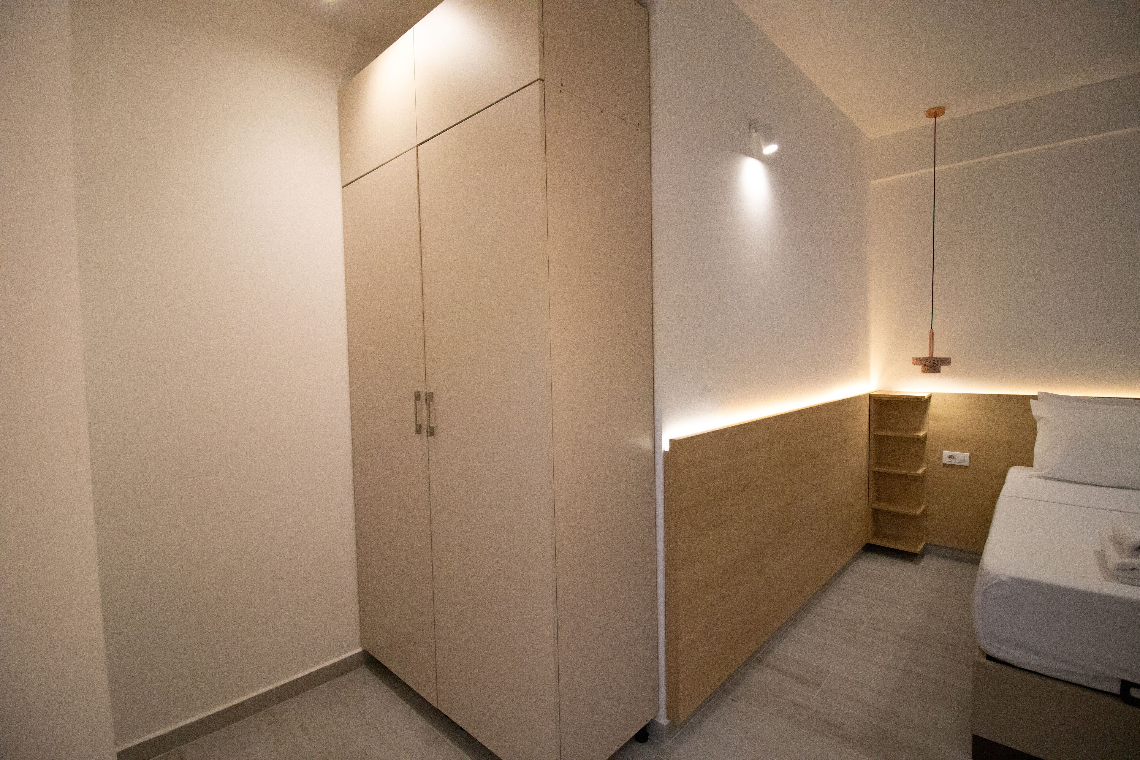 Une chambre moderne dotée d’une armoire intégrée, d’une table de chevet et d’un luminaire suspendu.