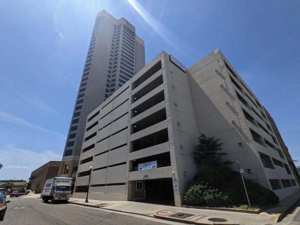 A multi-story parking garage with a modern design, adjacent to a tall building.