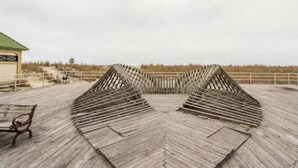 Ein Holzsteg führt zu einem Gebäude mit einem grünen Dach.