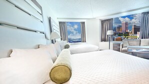 Ein Hotelzimmer mit einem großen Bett, einer Sitzecke, einem Schreibtisch und Blick auf eine Stadtlandschaft.