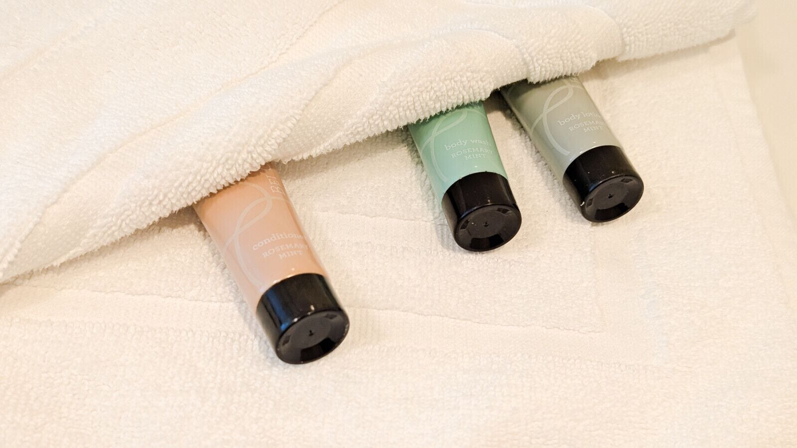 Trois bouteilles de gel douche sur une serviette blanche.
