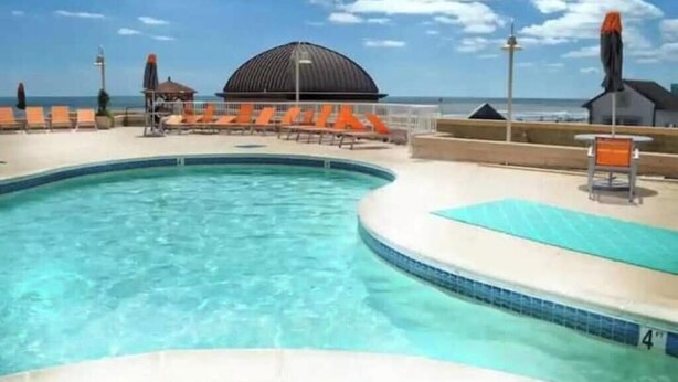 Ein Pool mit Liegestühlen und Blick auf den Strand.