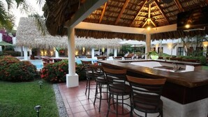 An outdoor bar area with a pool, thatched roof, and bar stools. - HOTEL VILLA BLANCA SUITES (San Juan Bautista Tuxtepec)
