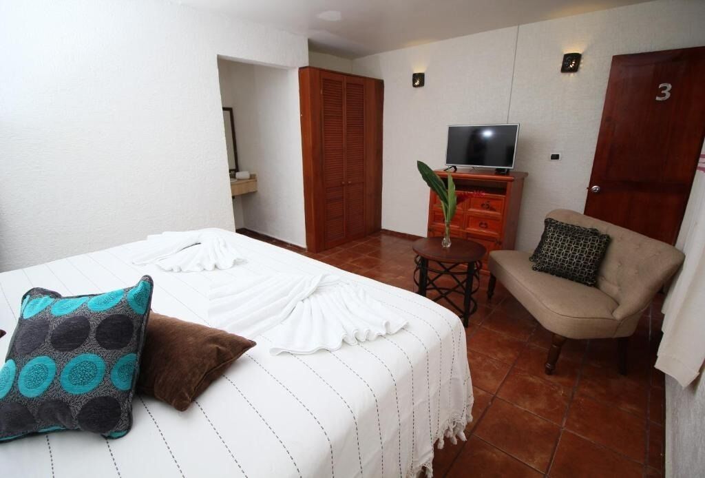 A hotel room with a bed, a sofa, a television, and a wardrobe.