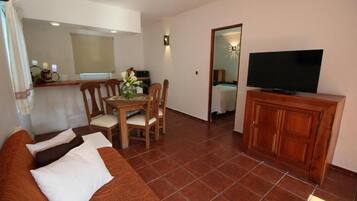 Una sala de estar con sofá, televisor, mueble de madera y un comedor con sillas y mesa.