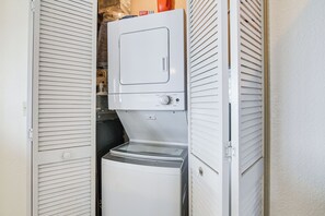Ein kleiner Waschraum mit Waschmaschine und Trockner, umgeben von weißen, durchbrochenen Türen.